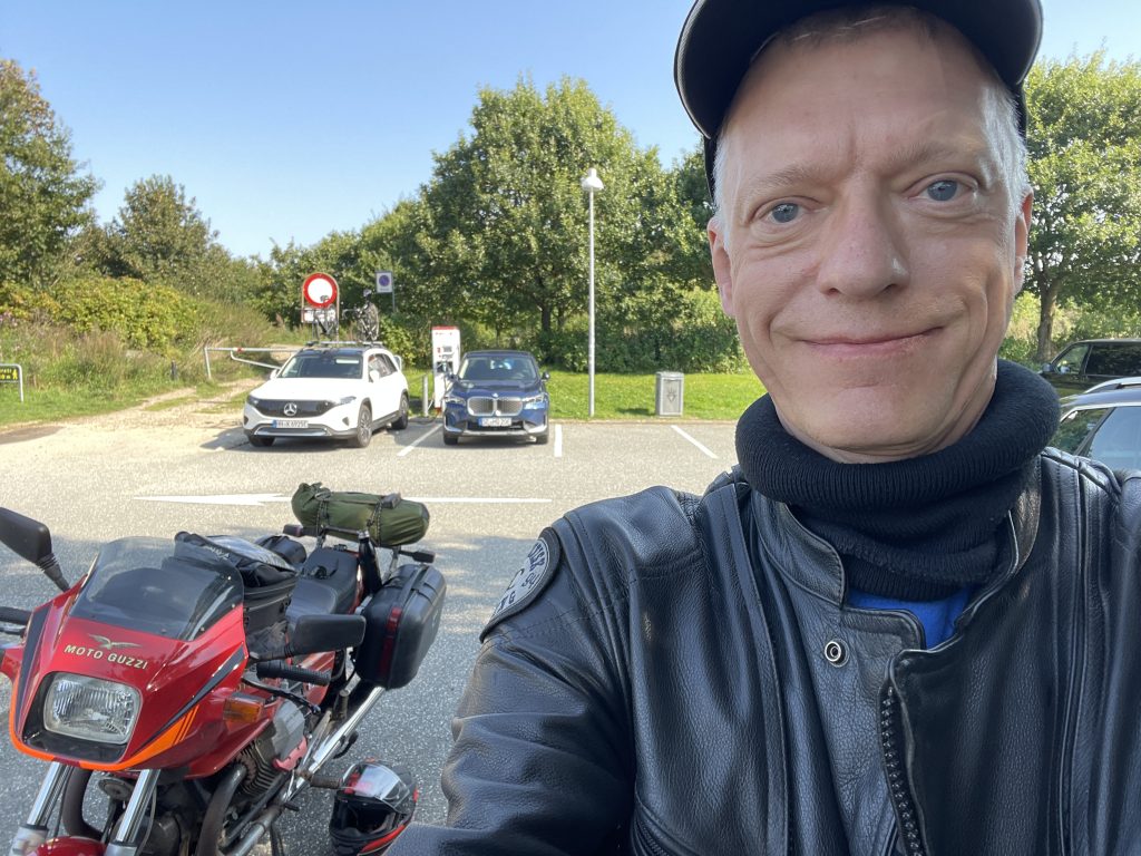 Selfie af Uffe med motorcyklen i baggrunden, taget på Skærup Øst rasteplads.