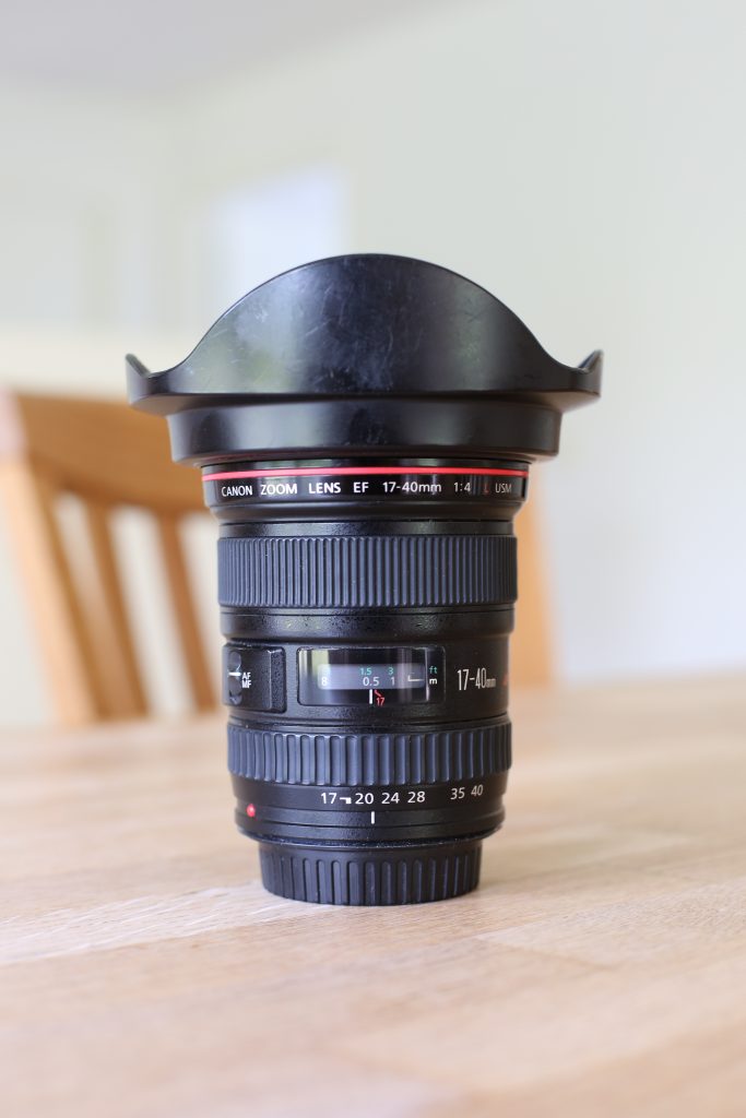 EF17-40 f/4L USM stående på et bord, med en stol i baggrunden. Billedet er taget med EF50mm f/1.4 og baggrundssløringen (bokeh) viser hvorfor det er Canons historisk mest populære 50mm.