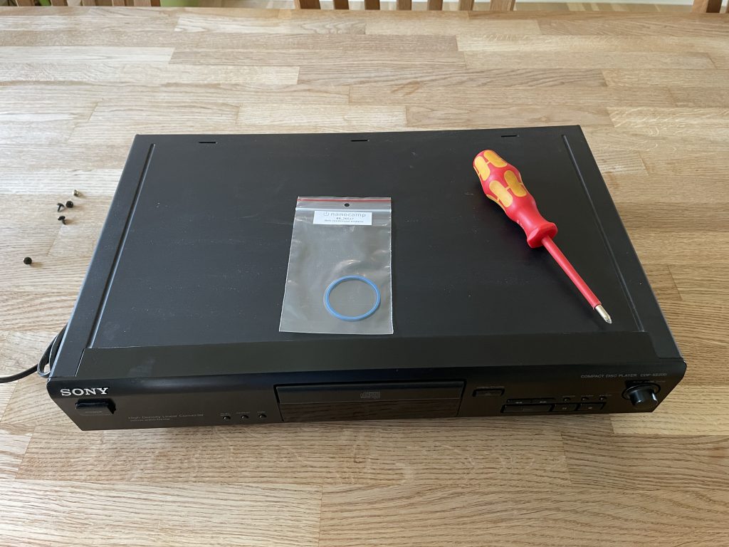 Sony Compact Disc Player CDP-EX200 on a table with replacement tray belt and a screwdriver on top.