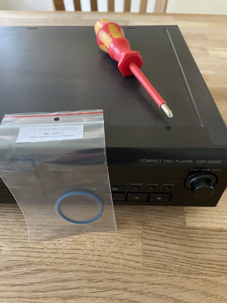 Sony Compact Disc Player CDP-EX200 on a table with replacement tray belt in front and a screwdriver on top.