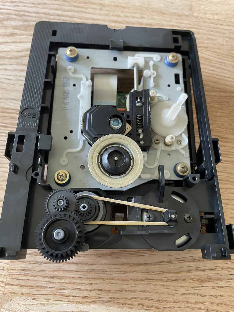 Sony Compact Disc Player CDP-EX200 CD tray assembly removed from chassis. An ordinary rubberband is seen on the belt wheels inplace of the original belt.